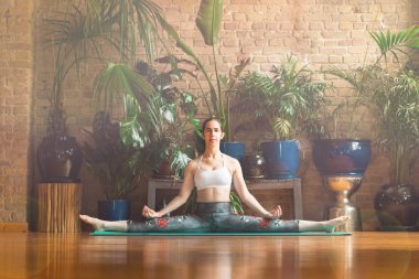 Stüdyoda yoga yapan genç bir kadın. Yeşil halıüzerinde oturmak.