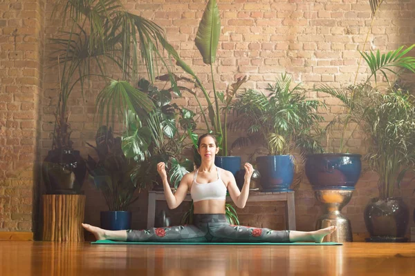 Jalá Mujer joven practicando yoga en estudio. Sentado en la alfombra verde . — Foto de Stock