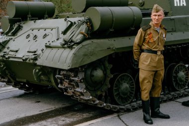 Verkhnyaya Pyshma, Rusya - 9 Mayıs 2019: Yeşil bir tankın yanında duran ince Sovyet askeri