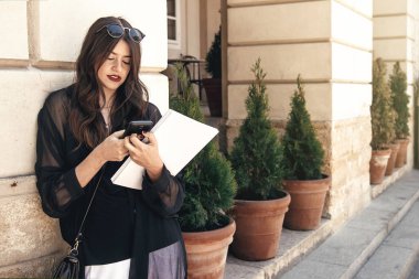 telefon kullanarak ve dergi şehirde sokak tutan güzel şık kadın. 