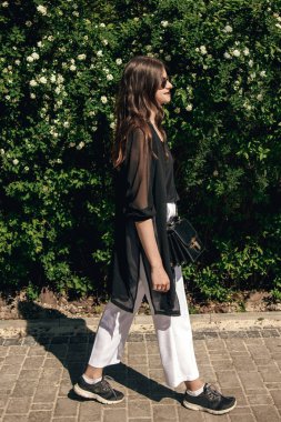 Şık Boho kadın güneşli yeşil Park'ta yürüyordunuz güneş gözlüklü. Tam boy