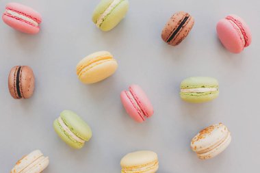 lezzetli renkli macaroons trendy pastel gri kağıt düz üzerinde yatıyordu. lezzetli pembe, sarı, yeşil ve kahverengi macaroons desen. metin için yer. nefis arka plan