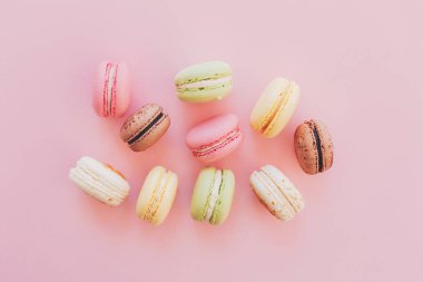 şık renkli macaroons trendy pembe kağıt, düz üzerinde yatıyordu. metin için yer. modern gıda fotoğrafçılığı kavramı. lezzetli pembe, sarı, yeşil, beyaz, kahverengi macarons. nefis arka plan