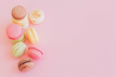 şık renkli macaroons trendy pembe kağıt, düz üzerinde yatıyordu. metin için yer. modern gıda fotoğrafçılığı kavramı. lezzetli pembe, sarı, yeşil, beyaz, kahverengi macarons. nefis arka plan