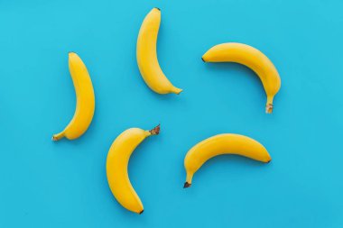 mavi kağıt trendy arka planda, düz sarı muz yatıyordu. Yaz parlak düz yatıyordu kavramı. sulu arka plan, pop sanat tarzı. modern resim, meyve görünümü top.