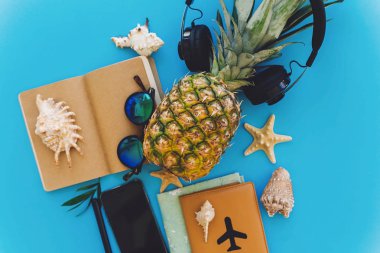 şık siyah telefon, pasaport, güneş gözlüğü, harita, şapka, kulaklık, kabukları, trendy mavi kağıt üstünde defter. metin için yer. yaz tatili düz planlama yatıyordu. seyahat ve yolculuk tutkusu