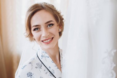 gülümseyerek, lüks düğün elbisesini, ipek elbise içinde duran güzel mutlu gelin. mutlu anlar. Evlilik kavramı. Gelin sabah hazırlanıyor