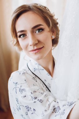 gülümseyerek, lüks düğün elbisesini, ipek elbise içinde duran güzel mutlu gelin. mutlu anlar. Evlilik kavramı. Gelin sabah hazırlanıyor