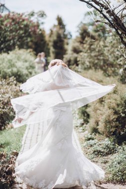 poz ve güneşli bahar park eğlenmek örtü ile güzel güzel gelin. yeşil bahçesinde duran mutlu kadın. mutlu bir evlilik anlar. kaçış kavramı