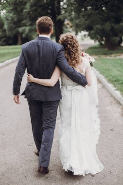 güzel güzel gelin ve güneşli parkta yürüyüş ve kucaklayan damat. mutlu evlilik çift yeşil bahçesinde sarılma. mutlu romantik anlar. kaçış kavramı