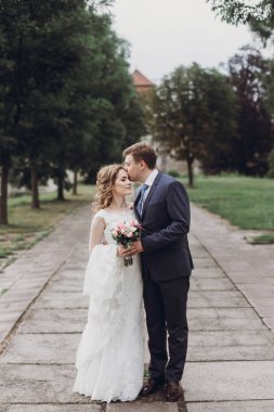 Sarılma ve açık havada yaz parkta öpüşme romantik yeni evli çift, düğün şık gelin elbise yürüyüşe ile yakışıklı damat