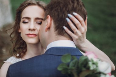 güzel güzel gelin ve damat öpüşme ve güneşli parkta yürüyüş. mutlu evlilik çift eski kale, yeşil bahçesinde sarılma. mutlu romantik anlar. kaçış kavramı