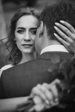 Şık düğün elbise huggin içinde güzel romantik gelin damat açık havada, güzel yeni evli gelin kameraya, Aile portre şehvetli bir bakışı