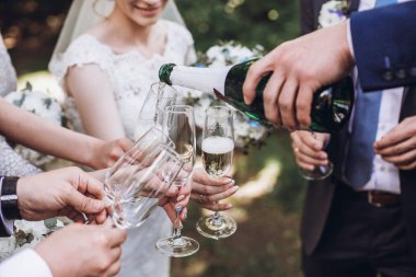 mutlu grup şampanya ile toasting insan. şişe şampanya tutarak ve içecek gözlük içine dökülen adam. nedime ve sağdıçlar eğleniyor. tatil kutlaması