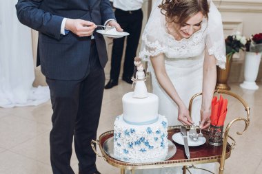 Yeni evli çift kesme pasta, düğün, Gelin ve damat lezzetli beyaz pasta dilimleme evli çift birlikte bağlı komik rakamlar ile dekore edilmiştir.