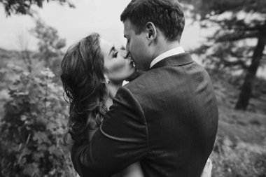 güzel güzel gelin ve damat öpüşme ve güneşli parkta yürüyüş. mutlu evlilik çift eski kale, yeşil bahçesinde sarılma. mutlu romantik anlar. kaçış kavramı