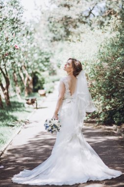 Güzel sarışın gelin zarif beyaz düğün elbise Park'ta yürüyordunuz kokulu