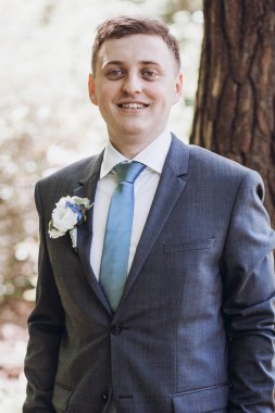 poz ve gülümseyen güneşli bahçede elbiseli güzel damat