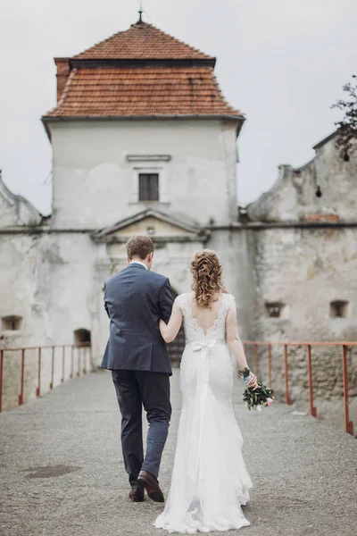 美しい豪華な花嫁と花婿を歩きます 幸せな結婚式カップル ハグと古城で抱きしめます 幸せなロマンチックな瞬間 駆け落ちのコンセプトです 官能的な愛 テキストのためのスペース — ストック写真