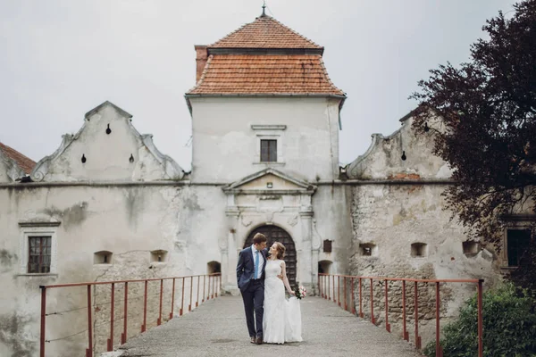 Mutlu çift kale, an düğün fairytale yürüyüş yeni evliler, güzel gelin ve damat sarılmak yakınındaki antik kale giriş Avrupa'da