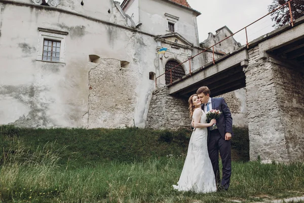 güzel güzel gelin ve damat öpüşme ve güneşli parkta yürüyüş. mutlu evlilik çift eski kale, yeşil bahçesinde sarılma. mutlu romantik anlar. kaçış kavramı