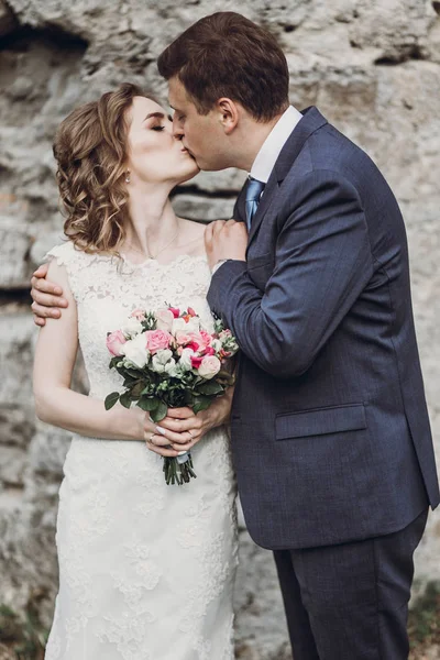 美丽华丽的新娘和新郎接吻 幸福的一对夫妇拥抱在绿色花园在老城堡 快乐浪漫的时刻 私奔的概念 感性的爱 — 图库照片