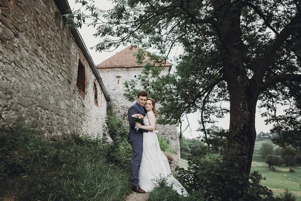 美しい豪華な花嫁と花婿のキスします 幸せな結婚式カップル ハグと古城で抱きしめます 幸せなロマンチックな瞬間 駆け落ちのコンセプトです 官能的な愛 テキストのためのスペース — ストック写真