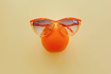 pastel sarı kağıt üzerinde güneş gözlüğü portakal, trendy düz yatıyordu. yaz tatil fikir. sulu meyve yiyin ve kavram diyet. pop sanat tarzı. yaratıcı minimalizm. metin için yer