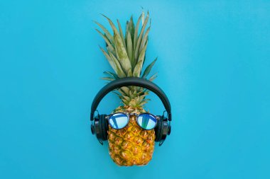 güneş gözlüğü ve trendy mavi Kağıt arka plan üzerinde kulaklık şık ananas. Yaz düz yatıyordu. Tatil ve parti genel kavram. metin için yer. hipster tatil