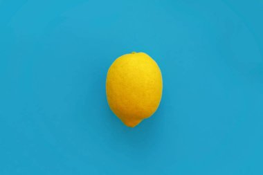 parlak sarı limon mavi kağıt düz üzerinde yatıyordu. trendy şık arka plan, meyve görünümü top. metin için yer