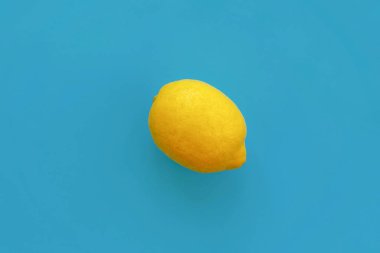 parlak sarı limon mavi kağıt düz üzerinde yatıyordu. trendy şık arka plan, meyve görünümü top. metin için yer