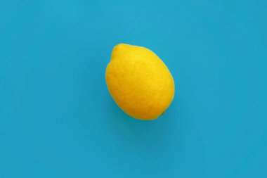 parlak sarı limon mavi kağıt düz üzerinde yatıyordu. trendy şık arka plan, meyve görünümü top. metin için yer