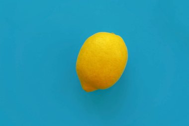 parlak sarı limon mavi kağıt düz üzerinde yatıyordu. trendy şık arka plan, meyve görünümü top. metin için yer