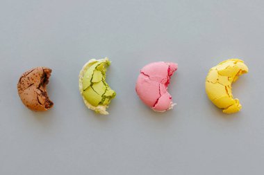 lezzetli ısırıldı sarı, pembe, yeşil veya kahverengi macarons trendy pastel gri kağıt, düz üzerinde yatıyordu. metin için yer. parti için lezzetli renkli macaroons şeker. nefis arka plan. Diyet kavramı