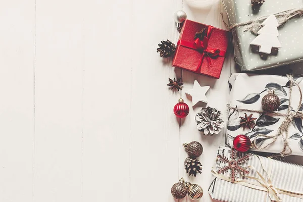 Moderne Kerstcadeautjes Verpakt Met Ornamenten Kegels Witte Houten Achtergrond Bovenaanzicht — Stockfoto