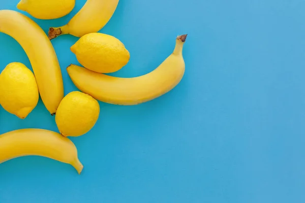 黄色いバナナと明るい青色の紙にレモン トレンディなフラットが横たわっていた 果物モダンなイメージ 平面図 ジューシーな夏のビタミンの抽象的な背景 ポップなアート スタイル ミニマリズム テキストのためのスペース — ストック写真
