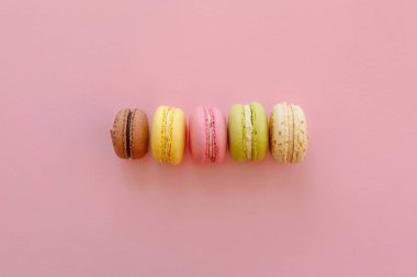 lezzetli renkli macarons trendy pastel üzerinde kağıt üstten görünüm pembe. metin pembe, sarı, yeşil, beyaz, kahverengi macaroons için alan. modern gıda fotoğrafçılığı kavramı. Lüks catering