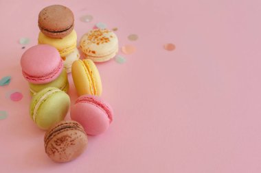 lezzetli renkli macarons konfeti ile trendy pastel pembe kağıt üzerinde. metin pembe, sarı, yeşil, beyaz, kahverengi macaroons için alan. modern gıda fotoğrafçılığı kavramı. Lüks catering