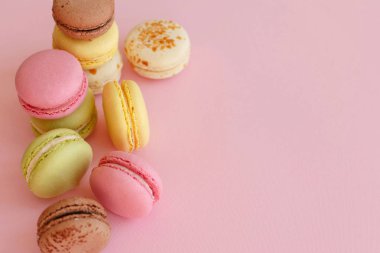 lezzetli renkli macarons trendy pastel üzerinde kağıt üstten görünüm pembe. metin pembe, sarı, yeşil, beyaz, kahverengi macaroons için alan. modern gıda fotoğrafçılığı kavramı. Lüks catering