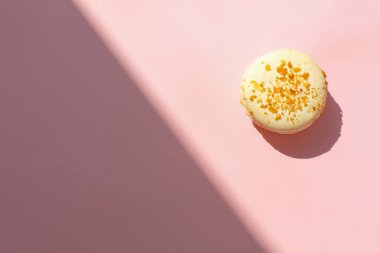 lezzetli beyaz macaron güneşli ışık trendy pastel pembe kağıt düz üzerinde yatıyordu. metin için yer. ışık aksine pembe acıbadem kurabiyesi. modern gıda fotoğrafçılığı kavramı. minimalizm kavramı