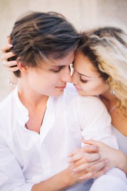 oturma ve güneşli sokakta kucaklayan aşık güzel mutlu çiftin yakın çekim. yavaşça sarılma ve öpüşme şık hipster damat ve sarışın gelin. yaz şehir tatile sokak romantik anlar