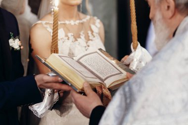 Rahip holding gospel. şık gelin ve damat ile rahip İncil Kilisesi Kutsal evlilik bağıyla, holding. manevi aşk çift düğün töreni sırasında.