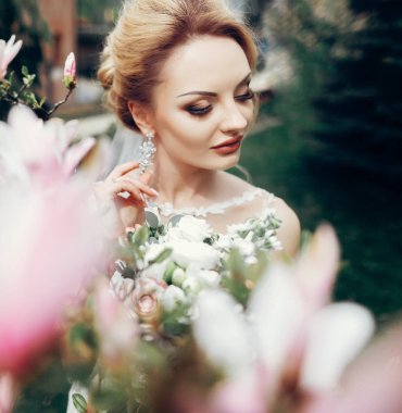 Çiçekler güzel gelin portresi. şık lüks makyaj bahar parkta blooming Manolya arasında sarışın kadınla. ihale şehvetli portre