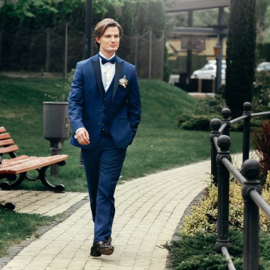 şık damat portre Park. yakışıklı adam mavi elbiseli bahar Park'ta yürüyordunuz. Beyefendi ya da işadamı resepsiyon açık havada
