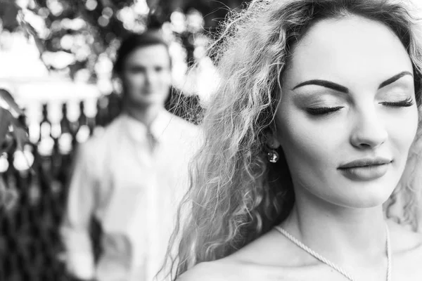 beautiful couple in love posing in sunlight  in city street. stylish hipster groom and blonde bride embracing. romantic moments in summer city on vacation. black white photo. woman close up