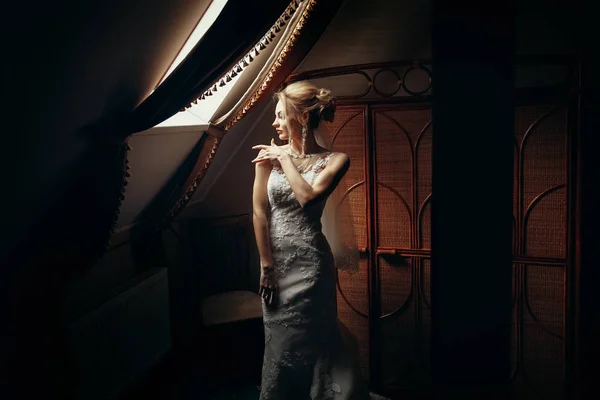 时尚的金发女郎 早上在酒店的橱窗里摆出一盏灯 结婚日的概念 美丽的女人肖像与惊人的耳环在白色礼服 — 图库照片