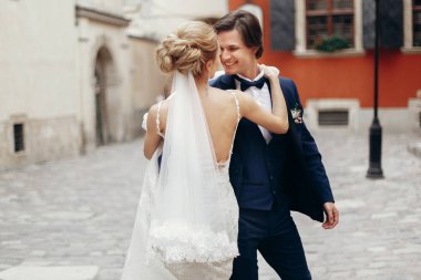 şık gelin ve damat dans ve şehir sokak kucaklayan. mutlu lüks düğün çifti ışığında eski binasında sarılma. Romantik duygusal an. kadın ve erkek gülümseyen