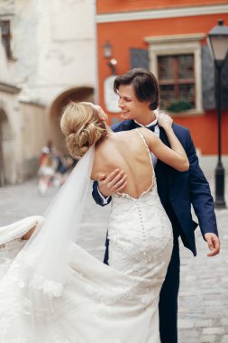 şık gelin ve damat dans ve şehir sokak kucaklayan. mutlu lüks düğün çifti ışığında eski binasında sarılma. Romantik duygusal an. kadın ve erkek gülümseyen