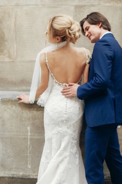 geri şık gelin ve damat şehir sokak kucaklayan. mutlu lüks düğün çifti ışığında eski binasında sarılma. Romantik duygusal an. kadın ve erkek gülümseyen ve öpüşme