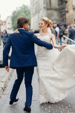 şık gelin ve damat dans ve having fun şehir sokak. mutlu lüks düğün çifti Holding ışıkta eller. Romantik duygusal an. duygusal erkek ve kadın